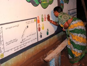 woman adding her handprint to board of colorful handprints